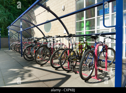 Fahrräder parken auf einem Parkplatz vor einem Bahnhof in England sicher undercover. Stockfoto