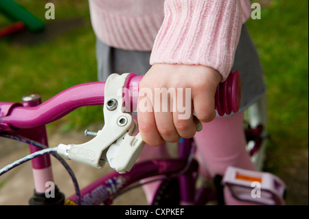 Nahaufnahme einer Kinderhand betätigen der Bremsen auf einem Fahrrad. Stockfoto