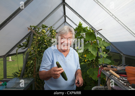 ältere Frau, die Pflege der Pflanzen im Gewächshaus Stockfoto