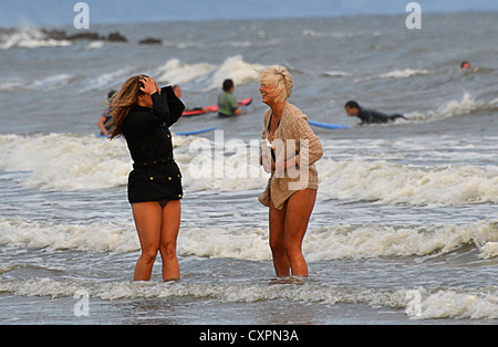 Zwei junge Damen im stürmischen Wind Paddeln im Meer bei Porthcawl Stockfoto