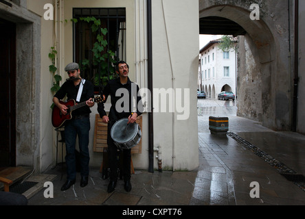 Zwei Straßenmusiker spielen Volksmusik außerhalb eine Wein-Bar in der alten Stadt von Spilimbergo, Friaul-Julisch Venetien, Norditalien Stockfoto