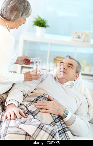 Porträt von Reife Frau mit Tabletten zu ihrem kranken Mann zu Hause Stockfoto