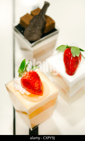 Käsekuchen mit Erdbeeren, dekoriert mit frischen Erdbeeren und Schokolade, serviert in einer Schüssel mit einem kleinen Stockfoto