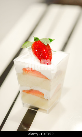 Käsekuchen mit Erdbeeren, dekoriert mit frischen Erdbeeren serviert in einer Schüssel mit einem kleinen Stockfoto