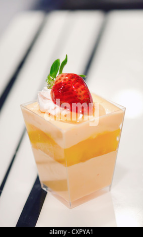 Orangen-Käsekuchen, dekoriert mit frischen Erdbeeren serviert in einer Schüssel mit einem kleinen Stockfoto