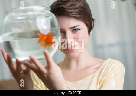 Junge Frau hält Goldfische in eine Schüssel geben Stockfoto