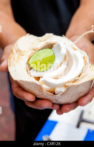 Person Holding Kokosnuss mit Kalk Stockfoto