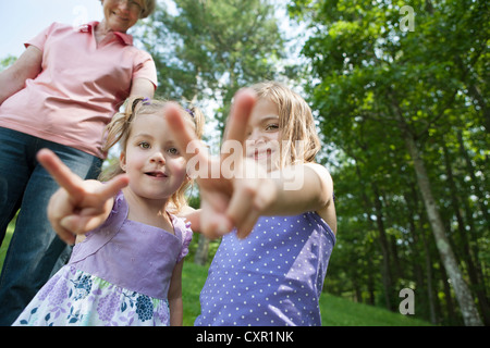 Mädchen machen Sieg mit Großmutter im Hintergrund zu unterzeichnen Stockfoto