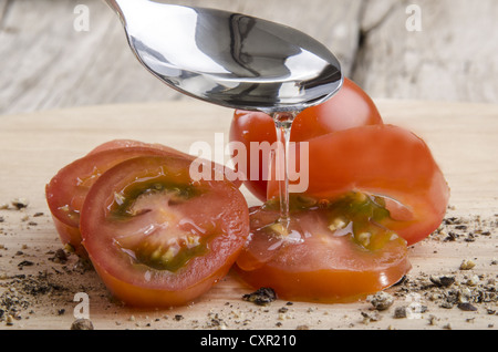 Olivenöl ergibt sich aus einem Löffel auf Cherry-Tomaten Stockfoto