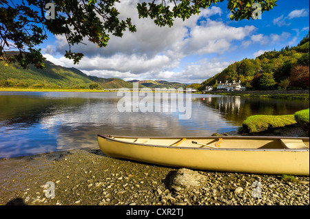 Ein gelbes Kanu im Vordergrund des Flusses Mawddach mit reflektierten blauen Himmel, Baum bedeckt Hügel, weiße Brücke im Hintergrund Stockfoto