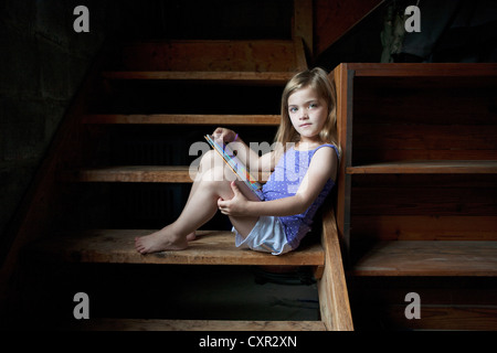 Mädchen sitzen auf Keller Schritt mit digital-Tablette Stockfoto