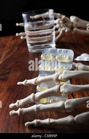 Skelett mit Tabletten und ein Glas Wasser in seine knöcherne Hand Stockfoto