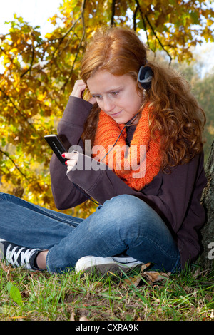 Rothaarige Mädchen Musikhören mit Kopfhörer mit iPod Stockfoto