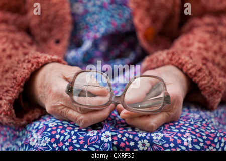 Hände einer alten Frau, die alte zerbrochene Gläser halten Stockfoto