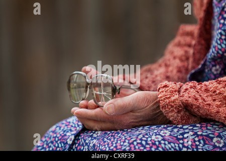 Hände einer alten Frau, die alte zerbrochene Gläser halten Stockfoto