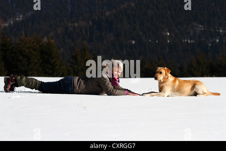 Frau mit einem Golden Retriever, liegend im Schnee, Thüringen, Deutschland, Europa Stockfoto