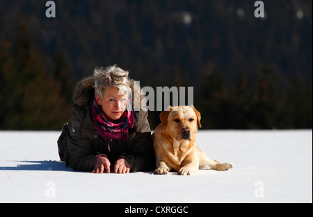 Frau mit einem Golden Retriever, liegend im Schnee, Thüringen, Deutschland, Europa Stockfoto