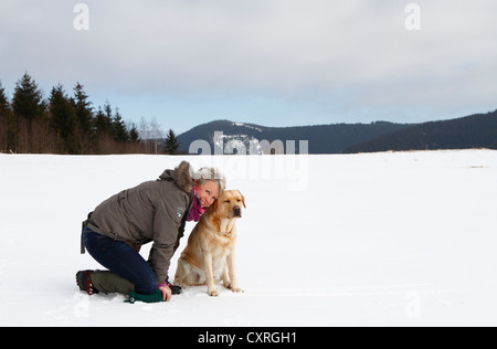 Frau mit einem Golden Retriever kniend im Schnee, Thüringen, Deutschland, Europa Stockfoto