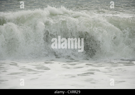 Eine große Welle brechen auf Chesil Beach, an der Küste von Dorset, bei stürmischem Wetter. England, United Kingdom. Stockfoto