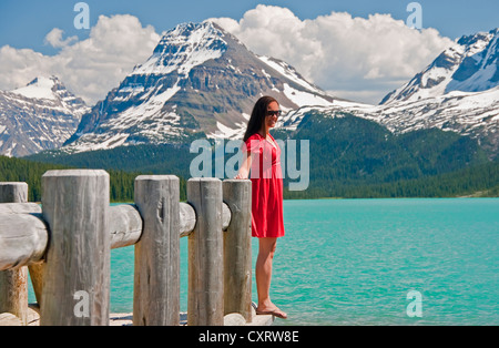 Junge Frau im roten Kleid am Bow Lake im Banff Nationalpark, Alberta Stockfoto