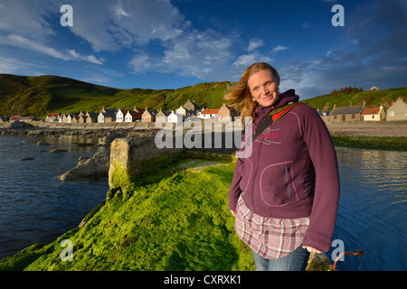 Schwangere Frau stand vor einer Küstenlandschaft mit grünen Algen auf Crovie Pier an der Fischerei Dorf Crovie Stockfoto