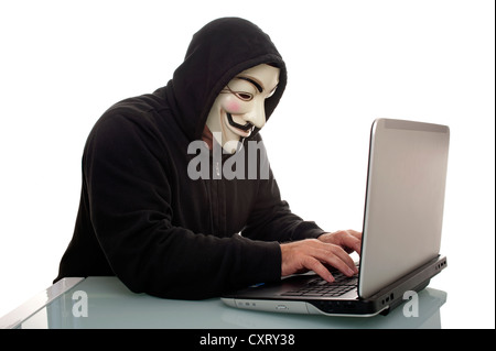 Mann trägt einen "Anonymous", Guy Fawkes oder "V for Vendetta" Maske, arbeitet auf einem Laptopcomputer Stockfoto