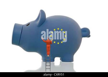 Figur Miniaturmalerei über Europäische Sterne auf ein blaues Sparschwein, symbolisches Bild Stockfoto