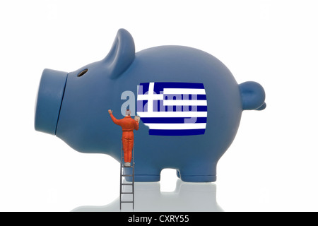 Miniaturmalerei Figur über eine griechische Nationalflagge auf ein blaues Sparschwein, symbolisches Bild Stockfoto