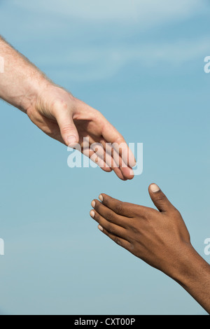 Westliche und östliche Hand schütteln vor blauem Himmel Stockfoto