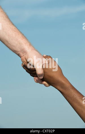Westliche und östliche Hand schütteln vor blauem Himmel Stockfoto