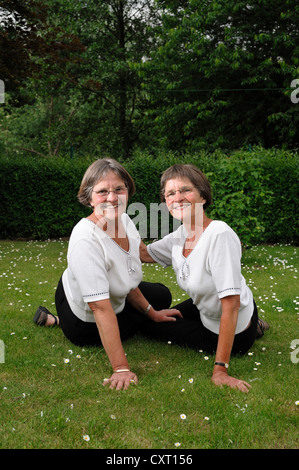 Zwei rüstige Zwillingsschwestern im Garten zu sitzen Stockfoto