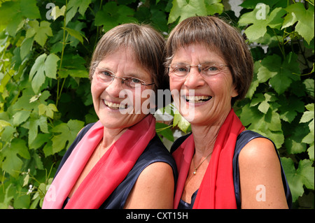 Lüsterne Zwillingsschwestern, gekleidet in roten Schals, gleichermaßen Porträt Stockfoto