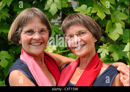 Lüsterne Zwillingsschwestern, gekleidet in roten Schals, gleichermaßen Porträt Stockfoto