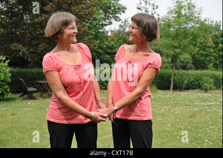 Zwei rüstige Zwillingsschwestern, Hand in Hand Stockfoto