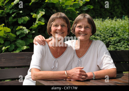 Zwei rüstige Zwillingsschwestern sitzen auf einer Bank Stockfoto