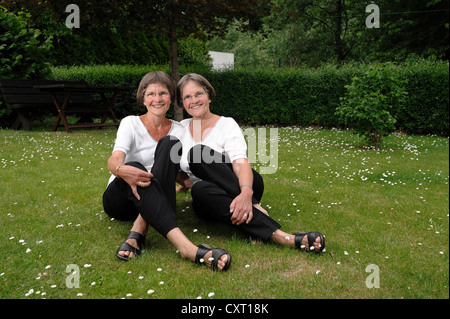 Zwei rüstige Zwillingsschwestern im Garten zu sitzen Stockfoto