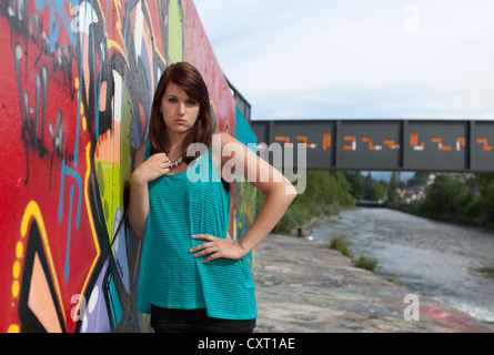 Junge Frau trägt ein türkises Top, schwarze Leggings und high Heels vor Wand mit graffiti Stockfoto