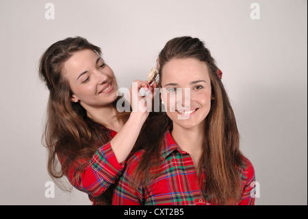 Zwillingsschwestern, eine Umsetzung einer Haarspange mit einer Rose in der anderen die Haare Stockfoto