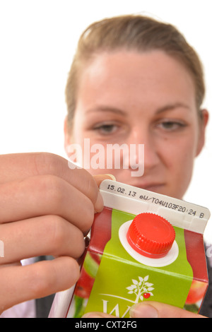 Frau, die Überprüfung der Mindesthaltbarkeitsdatum oder Verbrauchsdatum auf einem Getränke-Karton Stockfoto