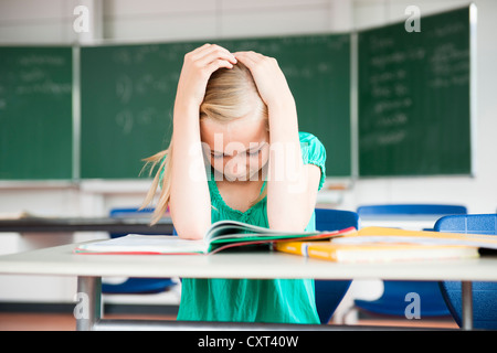 Schulmädchen in einem Klassenzimmer zu sitzen und grübeln über ein problem Stockfoto