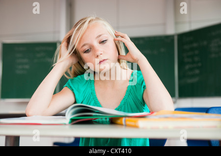 Schulmädchen in einem Klassenzimmer zu sitzen und grübeln über ein problem Stockfoto