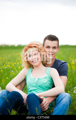 Lächelnd junges Paar sitzt auf einer Wiese Stockfoto