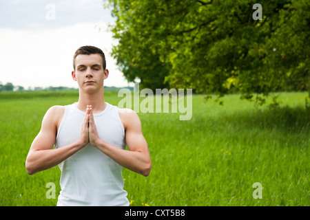 Junger Mann beim Yoga auf einer Wiese Stockfoto