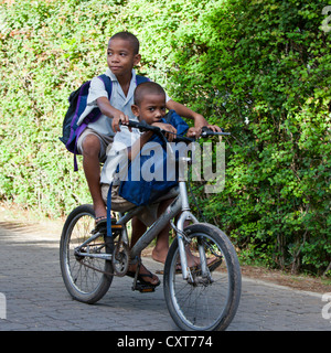 Zwei jungen, Kreolen, in Schuluniformen teilen ein Fahrrad auf dem Weg zur Schule, La Digue, Seychellen, Afrika, Indischer Ozean Stockfoto