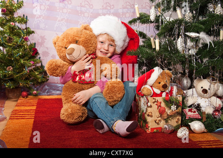 Mädchen, 4, hält einen Teddybären zu Weihnachten Stockfoto