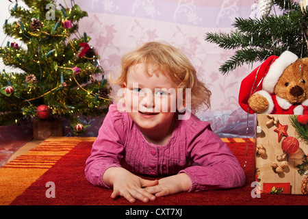 Glückliches Mädchen, 4, auf dem Boden liegend zu Weihnachten Stockfoto