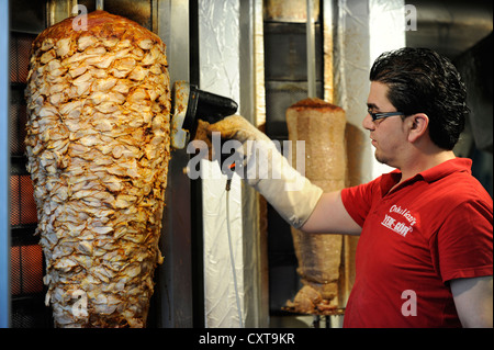 Arbeiter schneiden Döner aus einer rotierenden senkrechten Spieß in einem Kebab-Stand am Worringer Platz-Platz, Düsseldorf Stockfoto