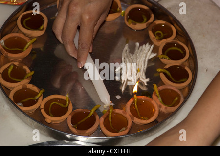 Verwenden eine Kerze, um eine Reihe von Öllampen als Teil des Diwali Gebete zu beleuchten. Öllampen sind gehalten in einem Teller, mit Öl gefüllt und angezündet. Stockfoto