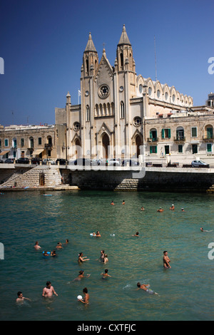 Menschen Baden im Mittelmeer vor der Karmeliterkirche in der Balluta Bay in Speisebereiche (San Giljan), Malta Stockfoto