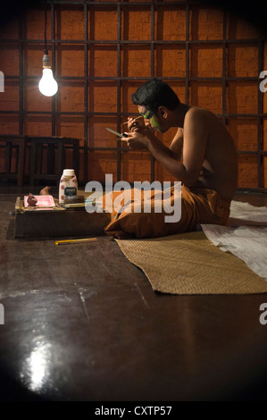 Vertikale Nahaufnahme Portrait des Kathakali Performancekünstlerin Anwendung machen Sie vor der Aufführung. Stockfoto